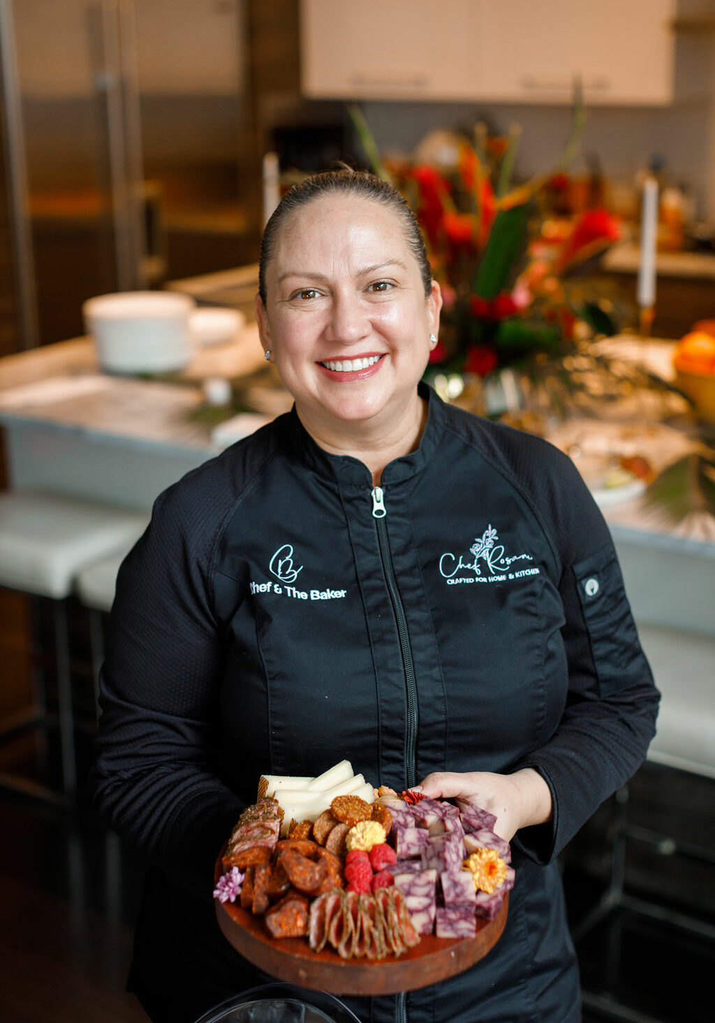 Chef Rosana standing in a kitchen smiling, holding food she has prepared